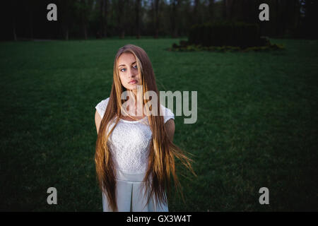 Young blonde girl illuminated by a magic lantern in the night mystery garden Stock Photo