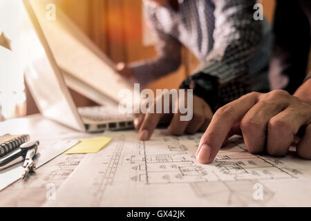 Two colleagues discussing data working tablet, laptop with on on architectural project at construction site at desk in office Stock Photo