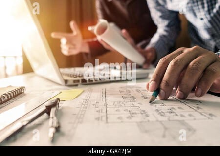 Two colleagues discussing data working tablet, laptop with on on architectural project at construction site at desk in office Stock Photo