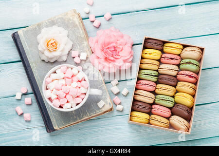 Colorful macaroons and marshmallow on wooden table. Sweet macarons in gift box. Top view Stock Photo