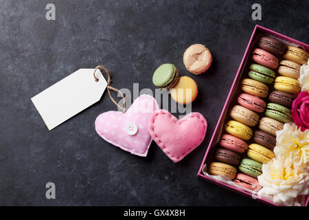 Colorful macaroons and greeting tag. Sweet macarons in gift box and hearts. Top view with copy space for your text Stock Photo