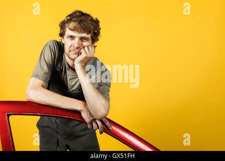 Handsome mechanic leans on the car's door yellow Stock Photo