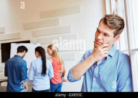 Young man as founder thinking next to business team Stock Photo