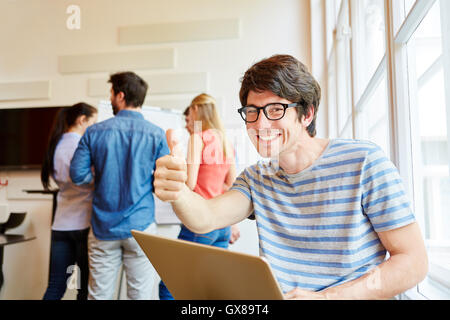 Nerd student holding thumbs up with a laptop Stock Photo