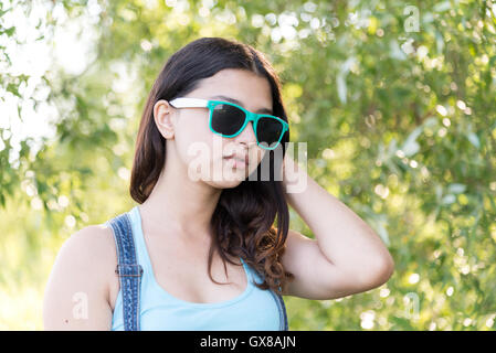 Portrait of girl with dark sunglasses on her head posing in shopping mall,  holding drink. Dressed in white t-shirt, blue trousers, black waist bag  Stock Photo - Alamy