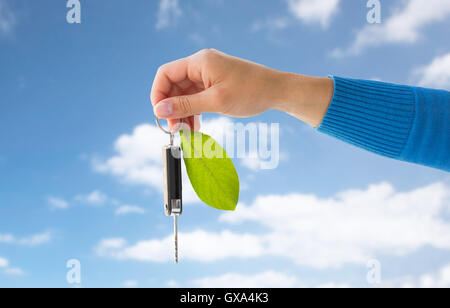 close up of hand holding car key with green leaf Stock Photo