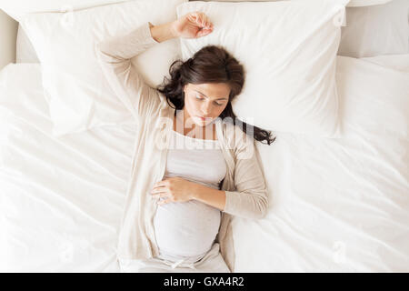 happy pregnant woman sleeping in bed at home Stock Photo