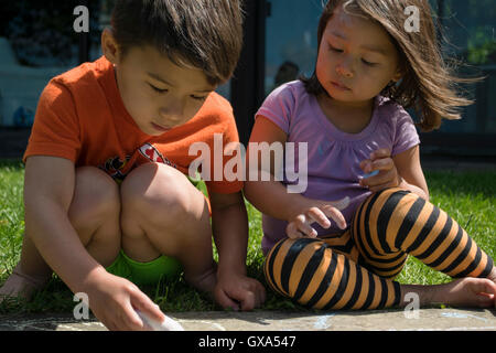 Pre-school child drawing with chalk in the yard Stock Photo