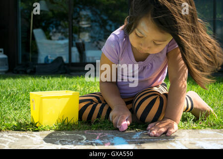 Pre-school child drawing with chalk in the yard Stock Photo