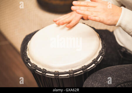 Drummer plays on small African drum, closeup photo with selective focus Stock Photo