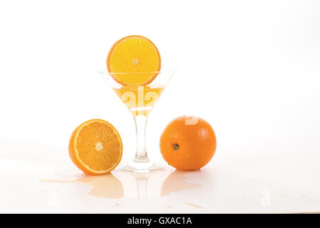 orange slice falls in a glass with a cocktail and raises a lot of splashes on white background Stock Photo