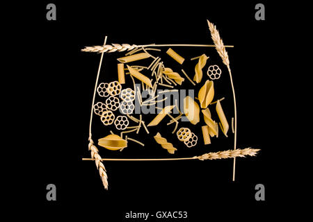 wheat ears as a frame around the pasta on a dark background Stock Photo