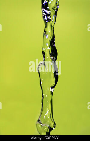 Water falling down, frozen in time with yellow background. Stock Photo