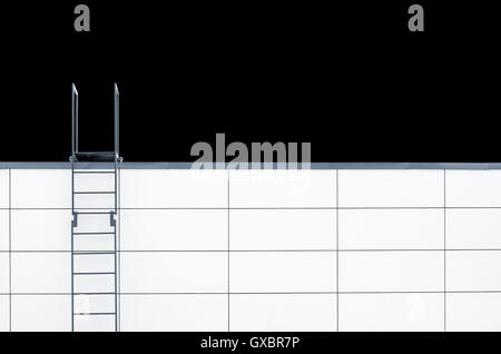 Metal emergency stairs on white wall isolated on black background. Minimalistic picture with plenty of copy space on the right Stock Photo
