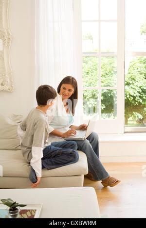 Mature woman and son using laptop on sofa Stock Photo