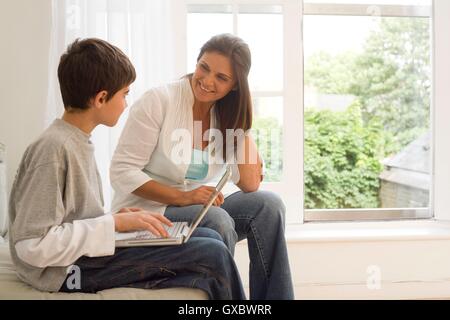 Boy and mother using laptop on sofa Stock Photo