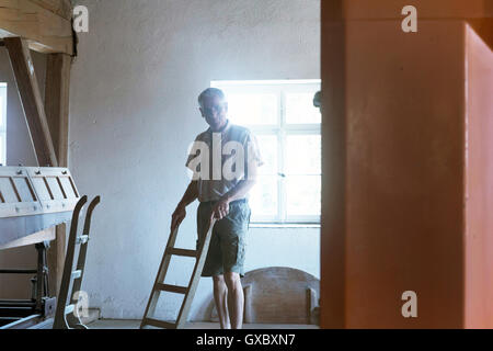 Male miller pushing sack barrow in wheat mill Stock Photo