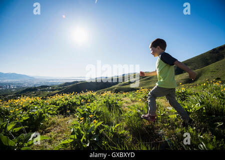 Young boy running in field, Bonneville Shoreline Trail in the Wasatch Foothills above Salt Lake City, Utah, USA Stock Photo