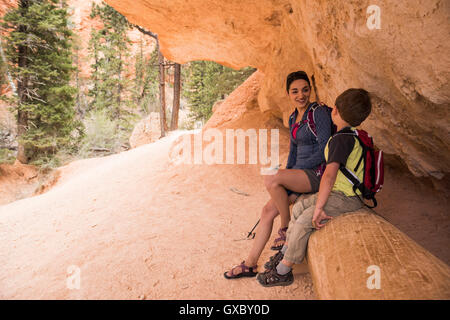 Mother and son taking a break, hiking the Queens Garden/Navajo Canyon Loop in Bryce Canyon National Park, Utah, USA Stock Photo