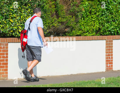 Royal Mail postman on his post delivery round in the UK. Stock Photo