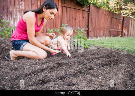 Mother and young daughter planting seeds in garden Stock Photo
