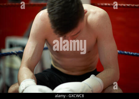 Boxer sitting in corner of boxing ring, exhausted Stock Photo