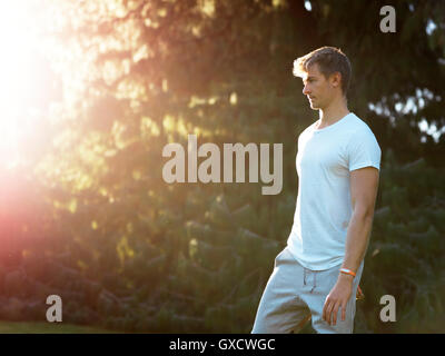 Young man standing outdoors, looking away Stock Photo