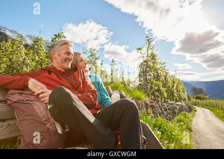 Couple relaxing on bench beside road, Meran, South Tyrol, Italy Stock Photo