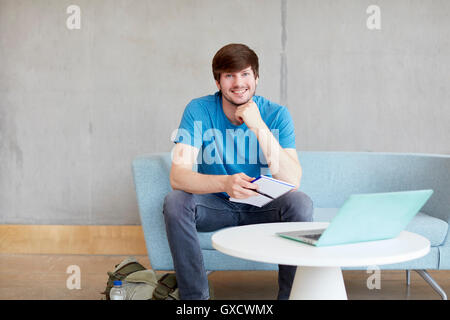 Portrait of young male student sitting on study space sofa at higher education college Stock Photo