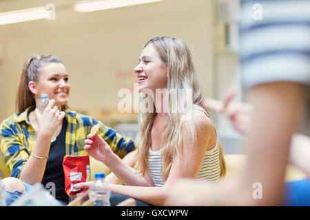 Two female students eating crisps in canteen at higher education college Stock Photo