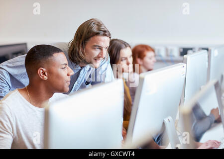 Male lecturer showing student using computer in higher education college computer room Stock Photo