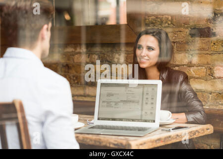 Young businessman and woman working with laptop and talking in cafe Stock Photo