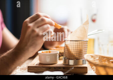 Hand of young man eating chips in restaurant Stock Photo