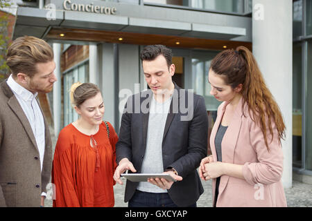 Businesswomen and businessmen looking at digital tablet outside office, London, UK Stock Photo