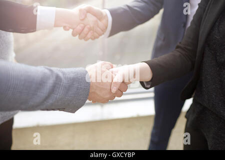 Mid section of businesswomen and businessmen shaking hands Stock Photo