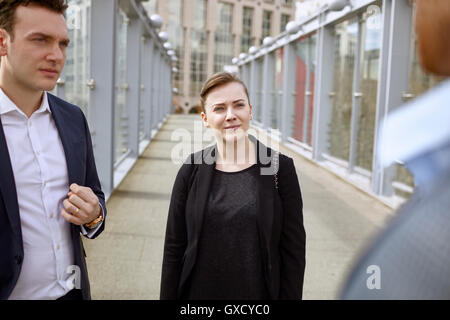 Businessmen and businesswoman having discussion on footbridge, London, UK Stock Photo