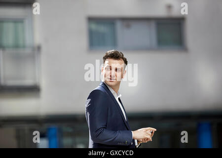 Businessman looking over his shoulder outside office, London, UK Stock Photo