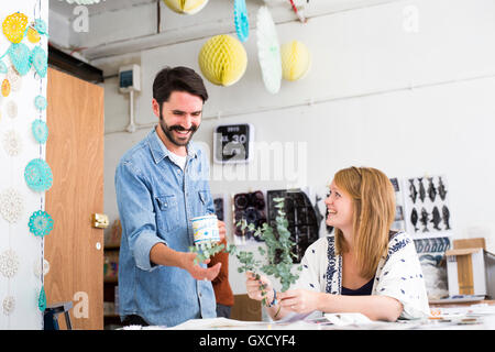 Female and male designer laughing at twig leaves in printing press studio Stock Photo