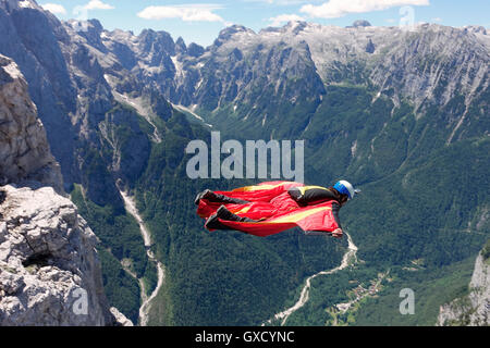 Wingsuit BASE jumper flying along cliff side and down the valley, Italian Alps, Alleghe, Belluno, Italy Stock Photo