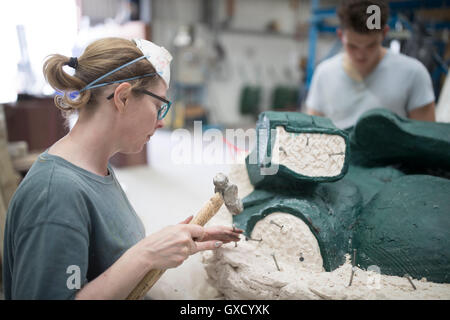 Female foundry worker removing mould from bronze sculpture in bronze foundry Stock Photo