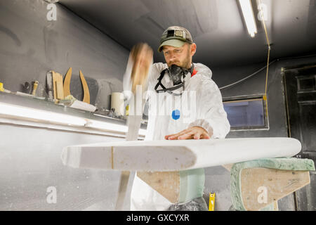 Male carpenter sawing surfboard in surfboard maker's workshop Stock Photo