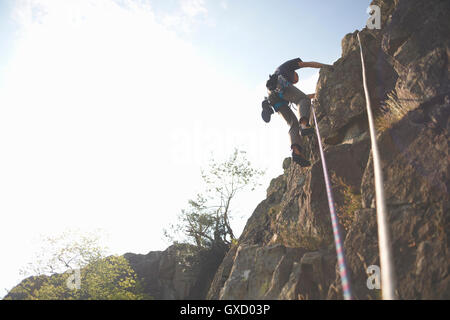 Low angle view of rock climber climbing rock face Stock Photo