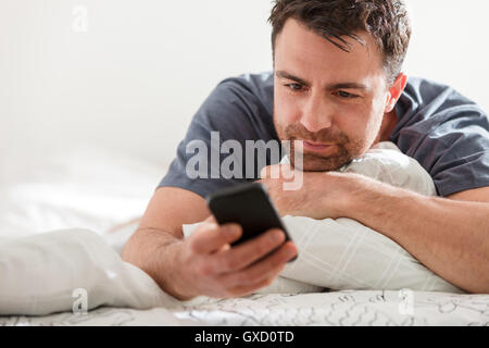 Man lying down using smartphone Stock Photo