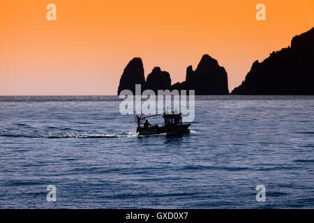 Silhouette of rocks and boat in sea, Capri, Amalfi Coast, Italy Stock Photo