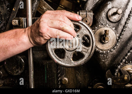 Close up of mans hand operating printing machinery in printing press workshop Stock Photo