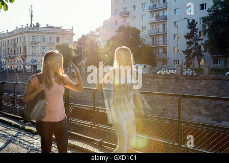 Two adult female friends giving high fiving each other in city, Vienna, Austria Stock Photo