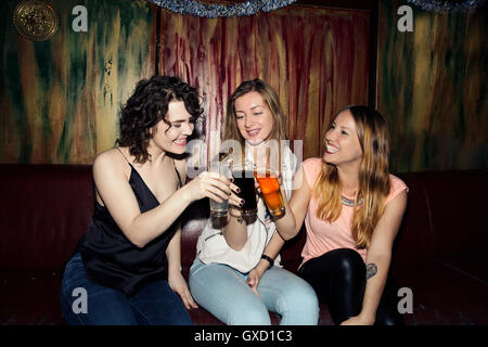 Three adult female friends raising a glass in bar Stock Photo