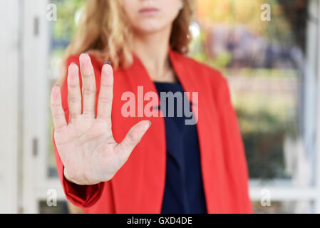 Girl in a red jacket makes stopping gesture open hand - close-up Stock Photo