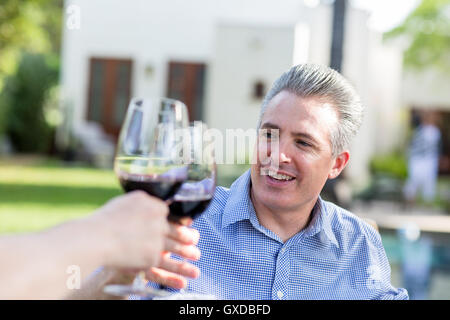 Mature couple making a red wine toast in garden Stock Photo