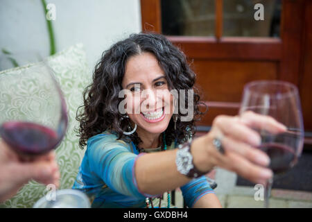 Over shoulder view of mature women making red wine toast at garden party Stock Photo